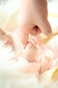 bébé tenant le doigt de sa maman